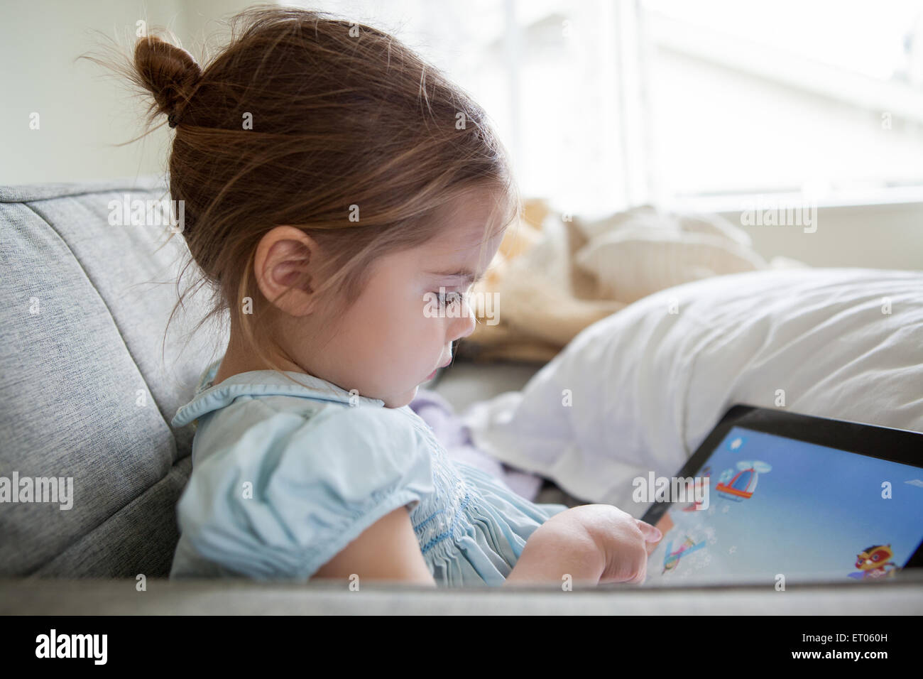 Girl using digital tablet on sofa Stock Photo