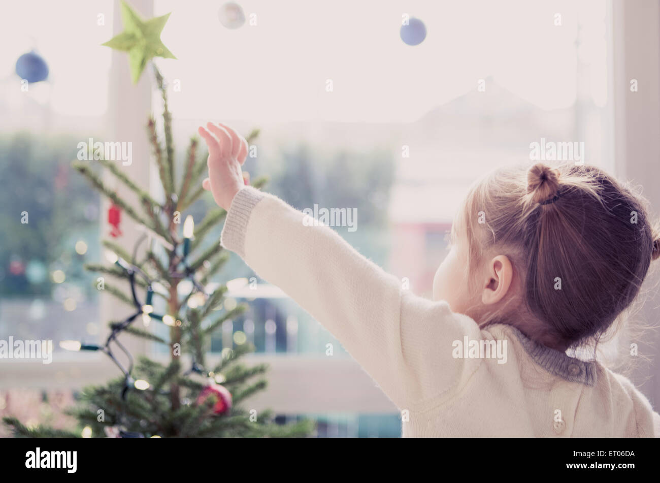 Girl reaching for start on Christmas tree Stock Photo
