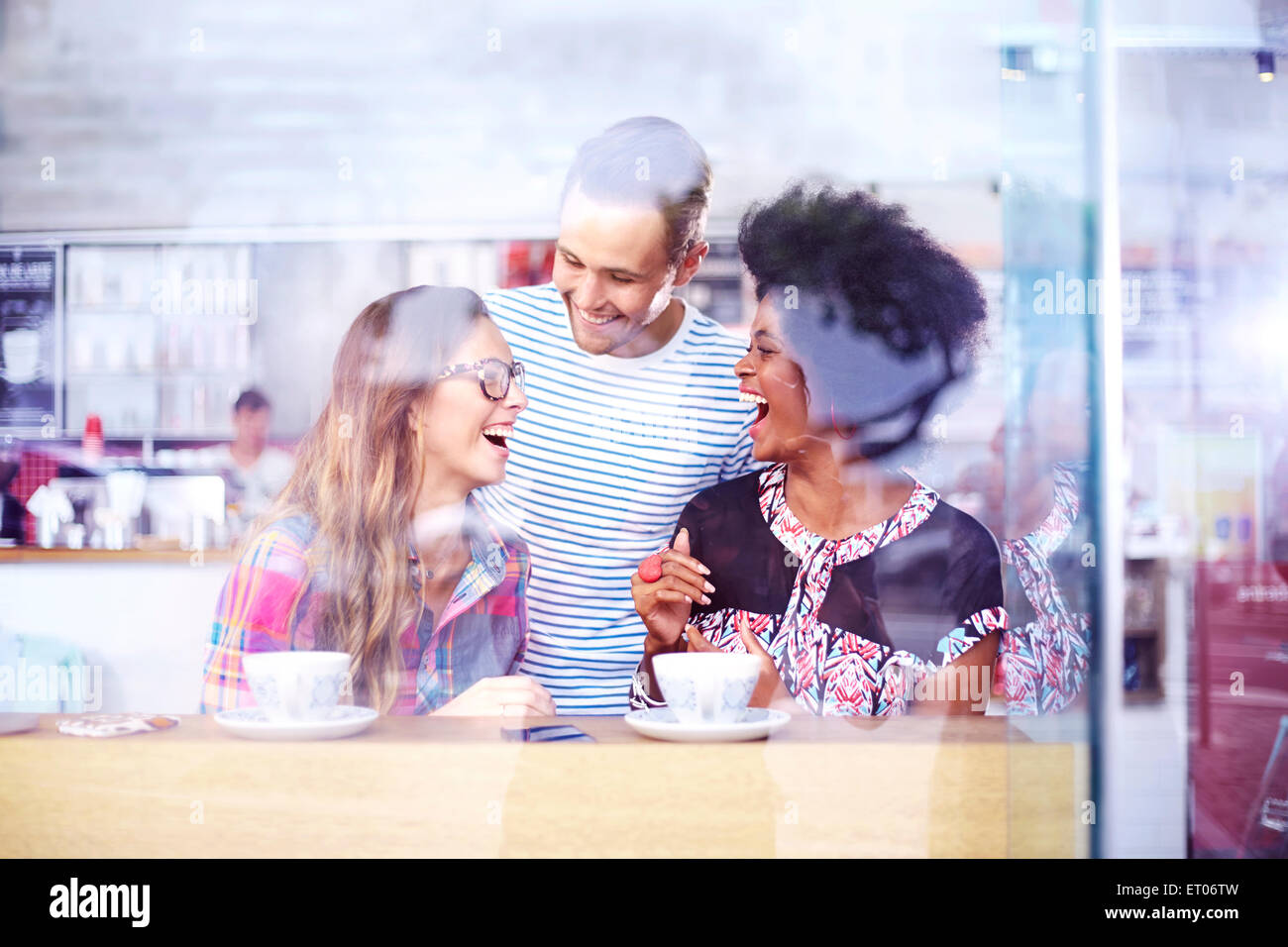 Friends laughing and drinking coffee in cafe Stock Photo