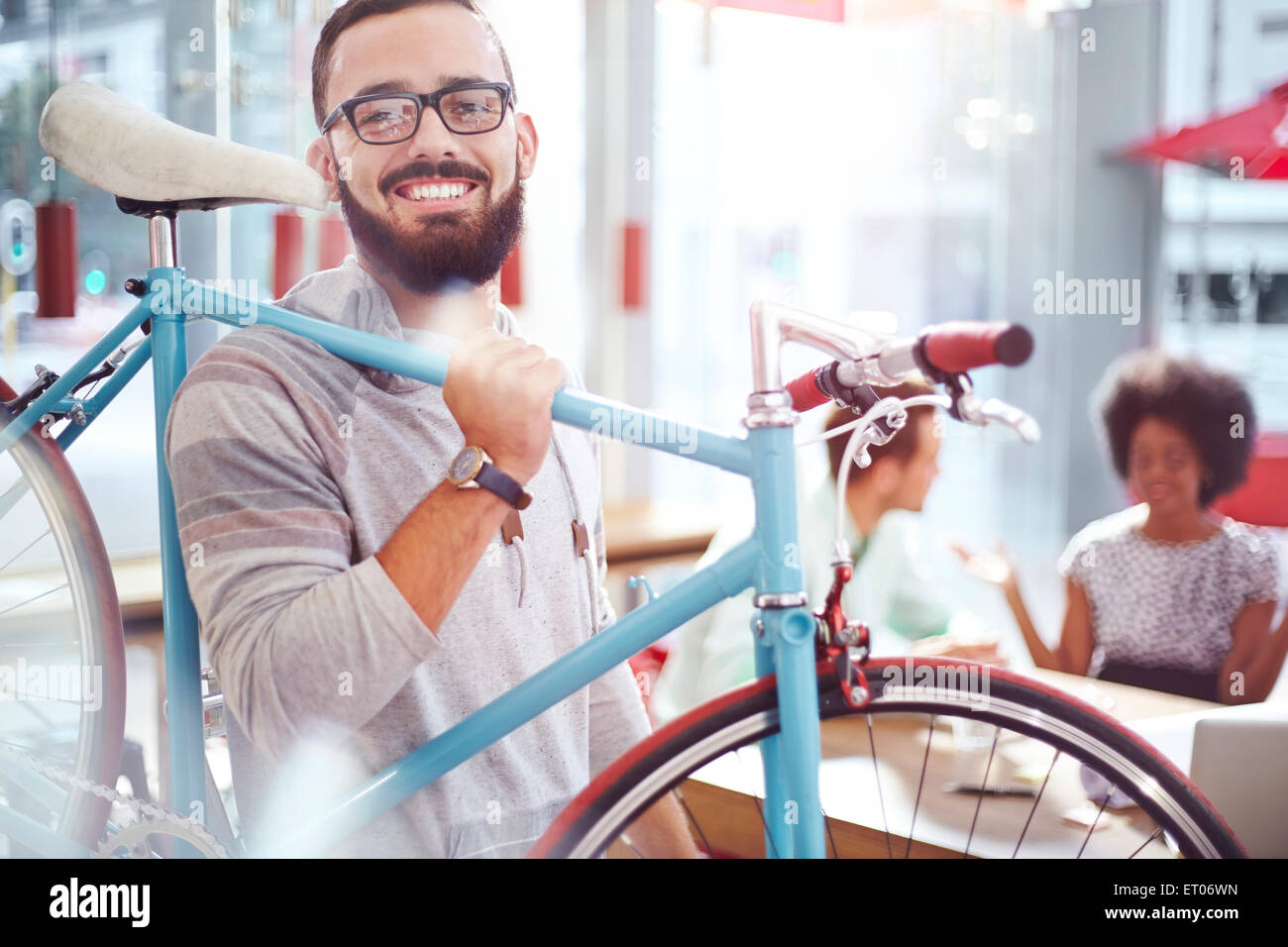 Smiling man carrying bicycle in cafe Stock Photo