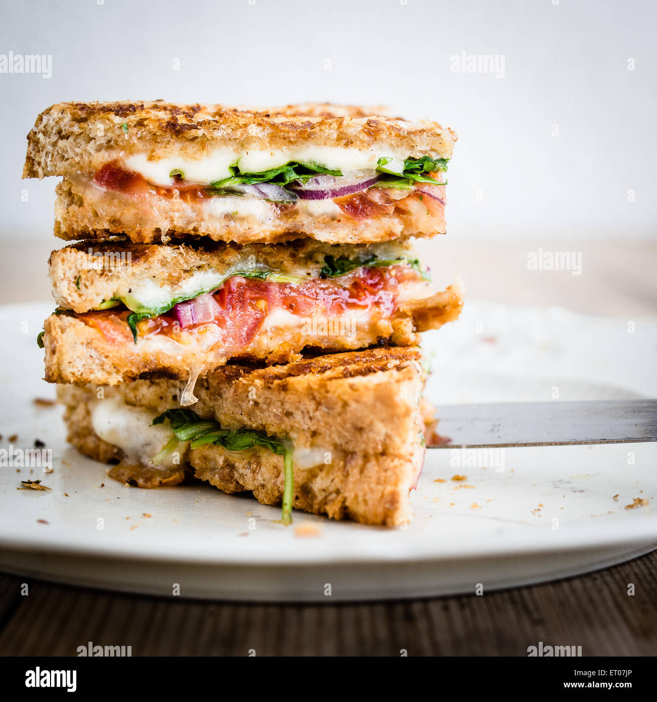 Vegetarian panini with tomatoes and mozzarella on rustic wooden table. Selective focus. Stock Photo