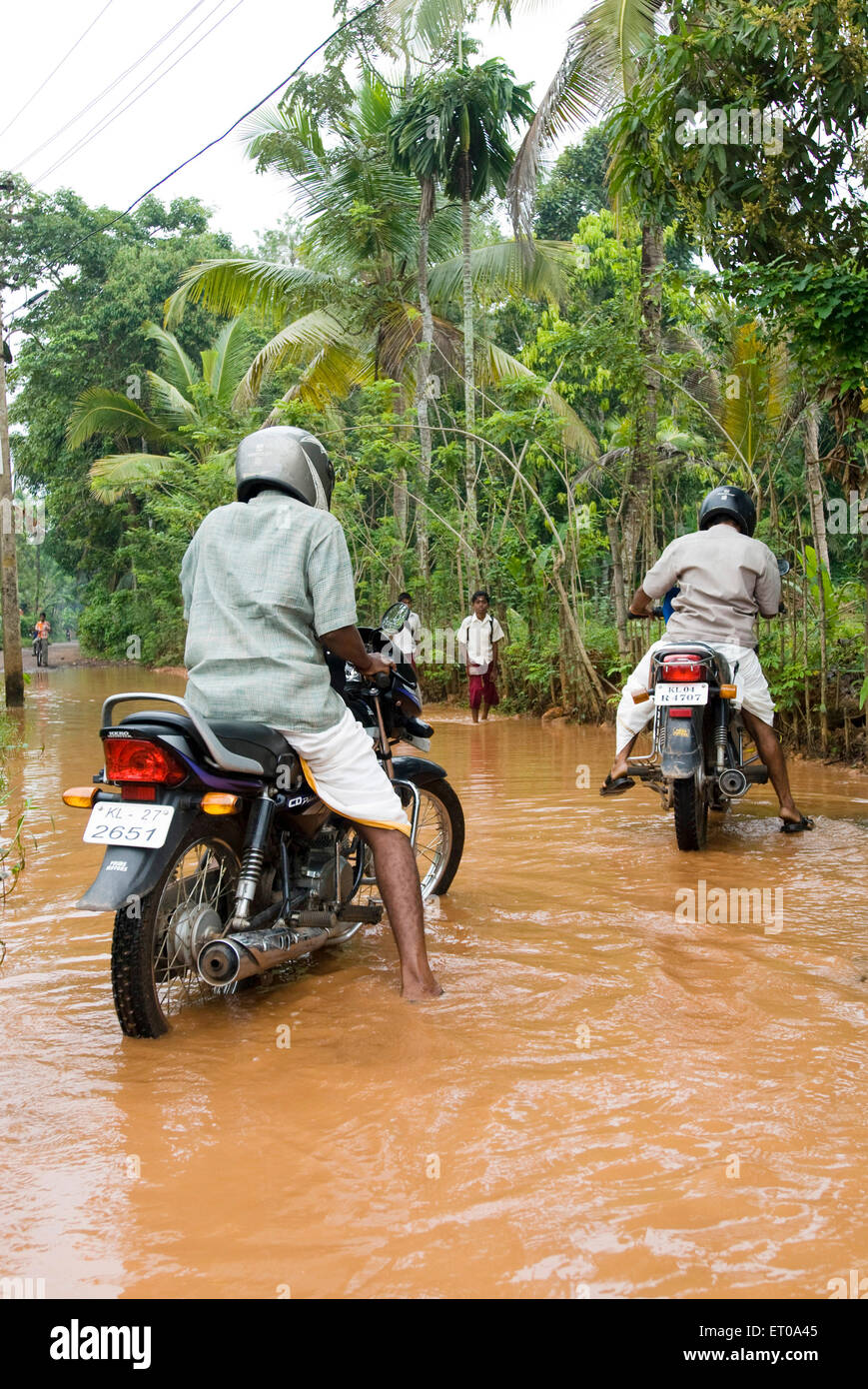 Men riding bikes in monsoon ; Kerala ; India Stock Photo