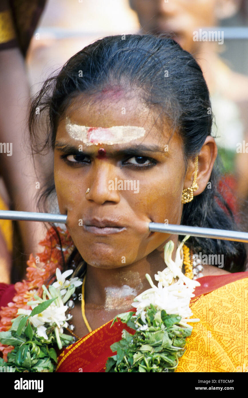 Woman piercing iron rod through cheeks discharging vow in Mariamman festival ; Tamil Nadu ; India NO MR Stock Photo