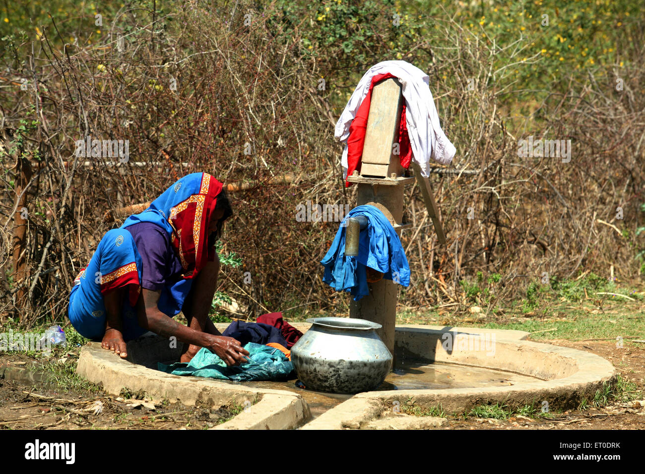 Lady washing clothes at village water pump in Jharkhand ; India Stock