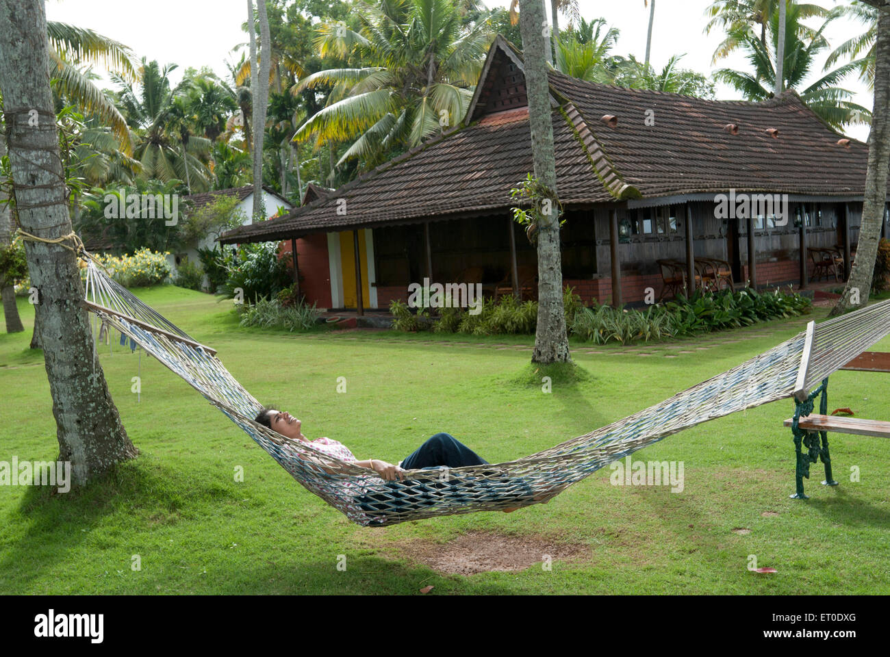 Lady resting in hammock in heritage lake resort ; Kuttanad ; Alleppey