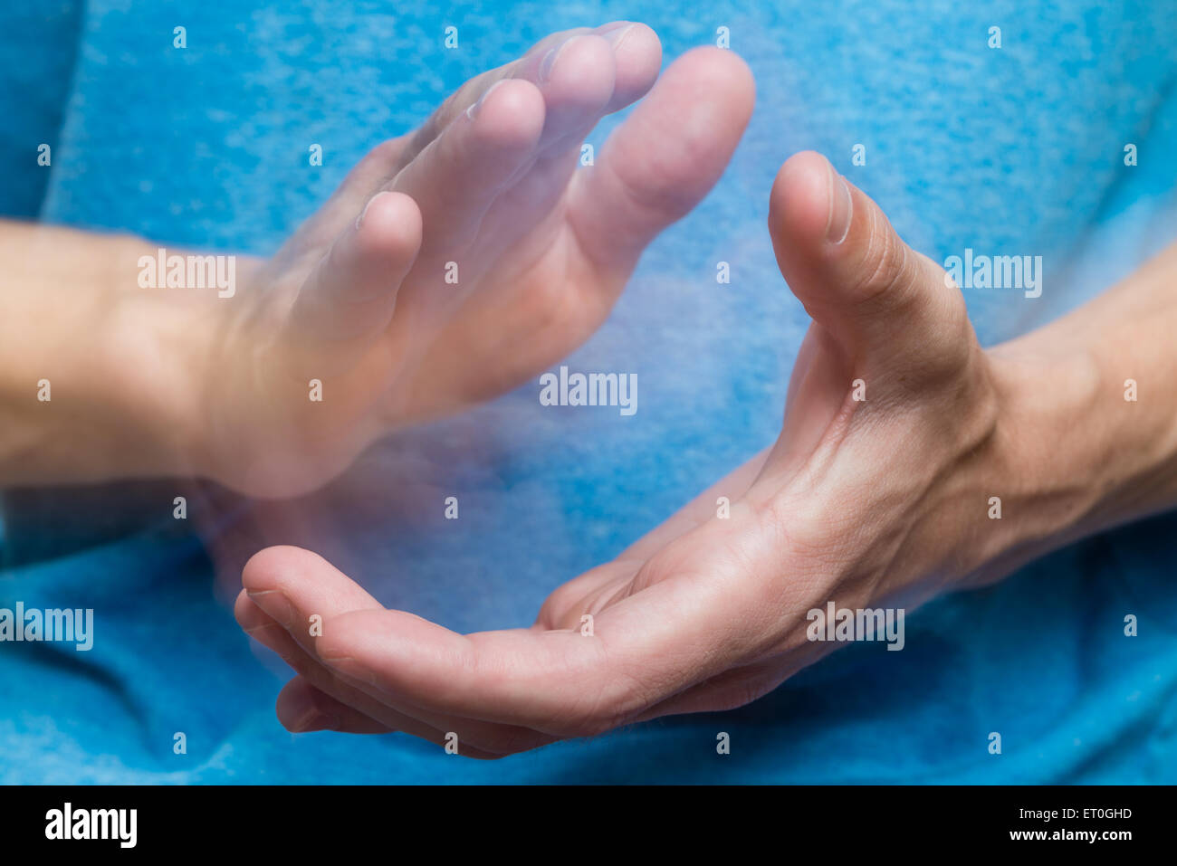A man's hands clapping with a light blue shirt in the background. Stock Photo