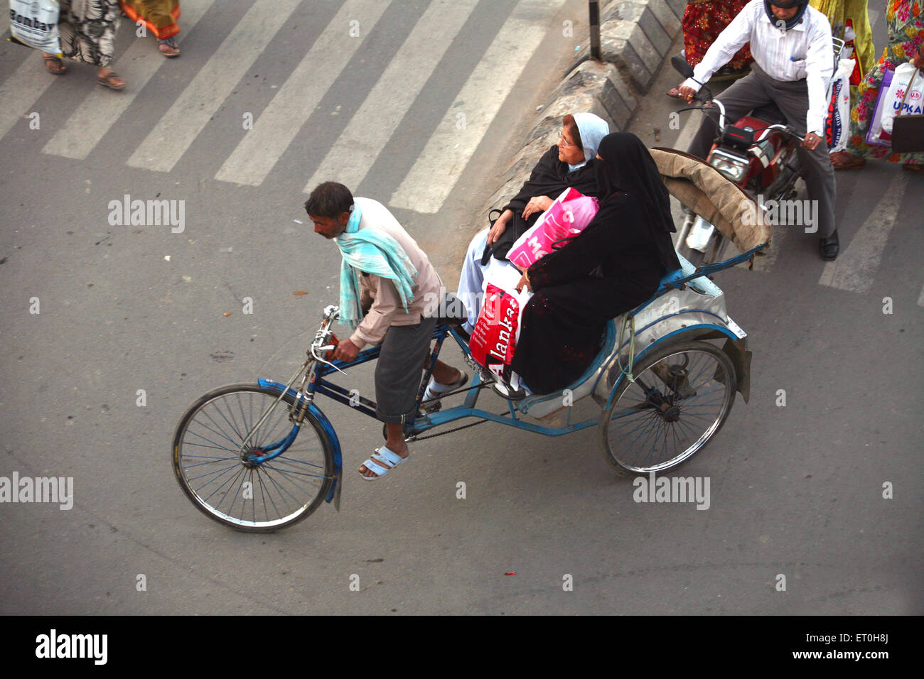 Two women riding on tricycle rickshaw pulled by rickshaw driver in Ranchi city capital of Jharkhand ; India Stock Photo