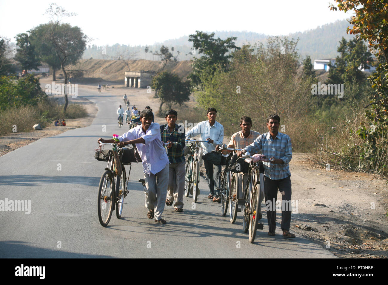 Workers from coal mine carrying lump of coal loaded back seat of bicycles in Jharkhand ; India NO MR Stock Photo