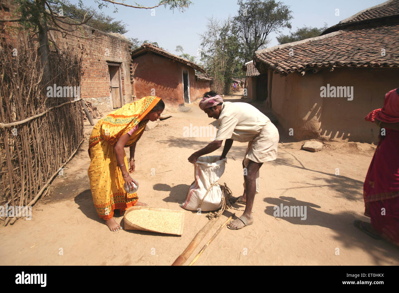 Lady buying grain from traditional merchant in exchange of old things in village in village in Jharkhand ; India NO MR Stock Photo