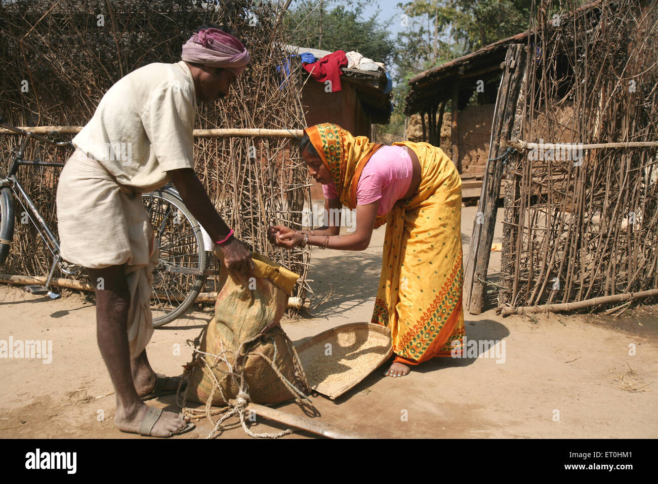 Lady buying grain from traditional merchant in exchange of old things in village in village in Jharkhand ; India NO MR Stock Photo