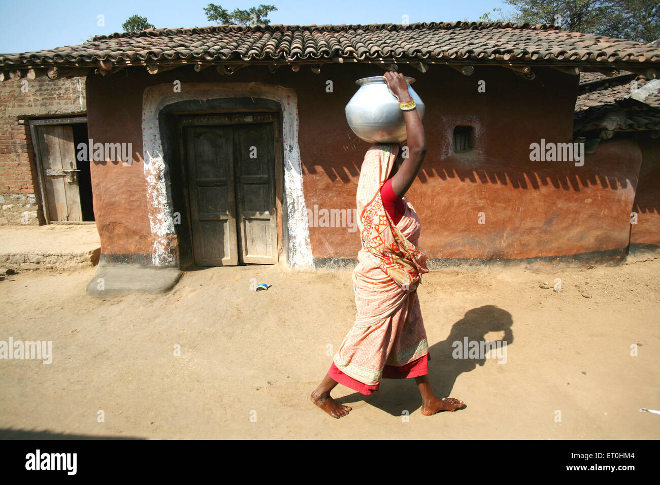 Indian rural woman carrying water pot on head in village road, Ranchi
