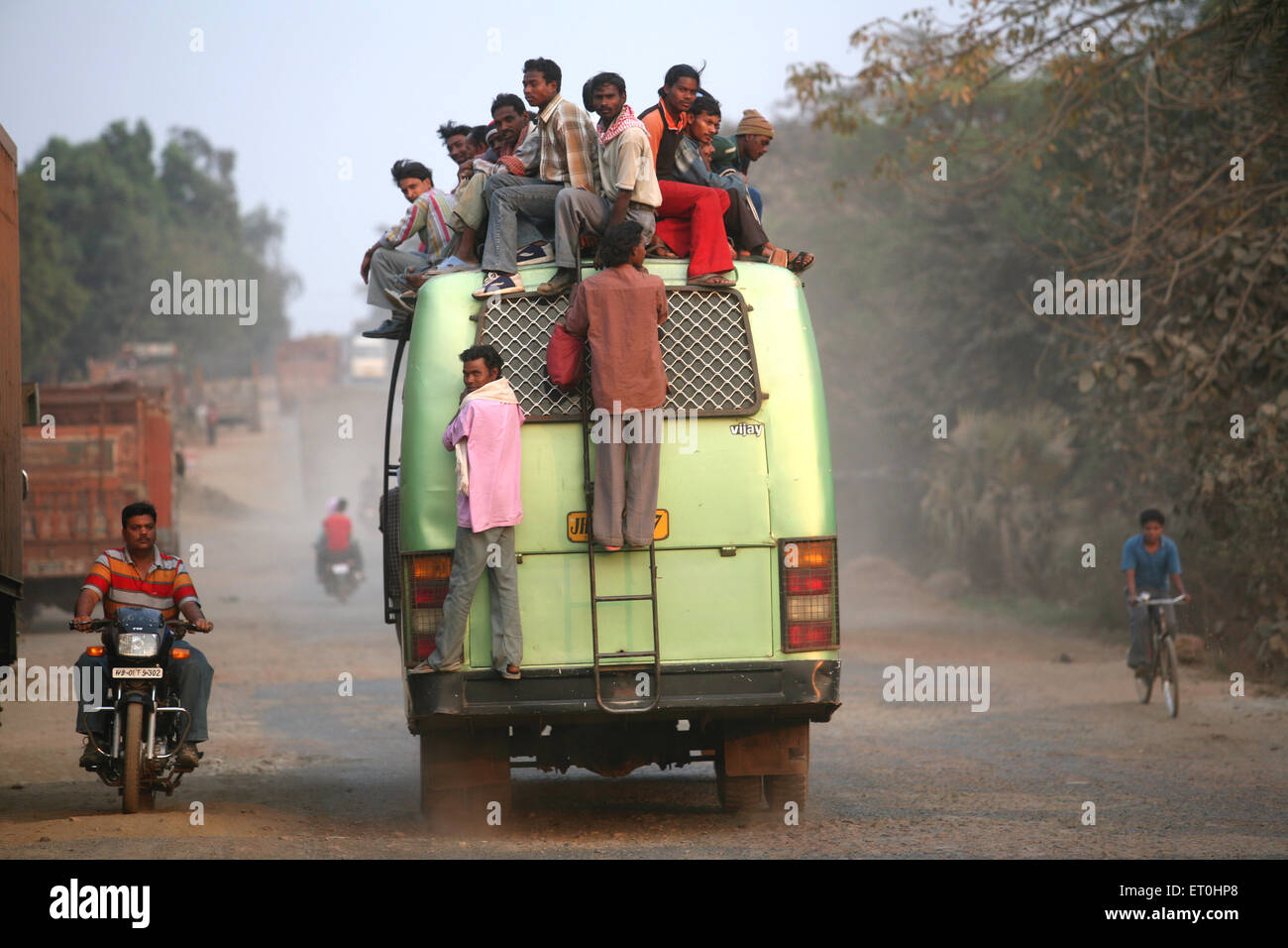 Passengers sitting on top of bus used local transport system in Jharkhand ; India Stock Photo