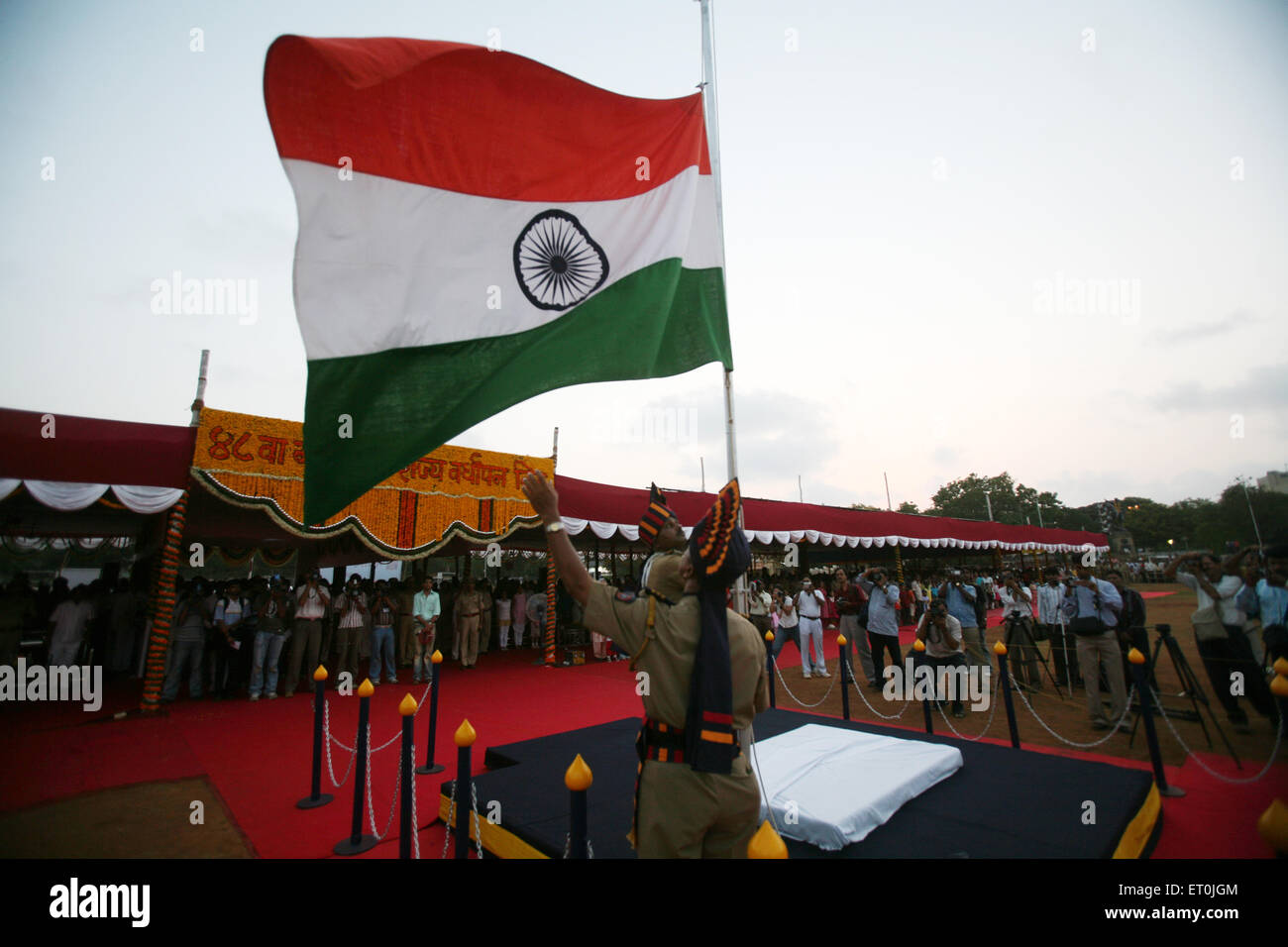 Police man bringing National Flag down sunset on 1 May Maharashtra state foundation day ; Shivaji park ; Dadar ; Mumbai Stock Photo