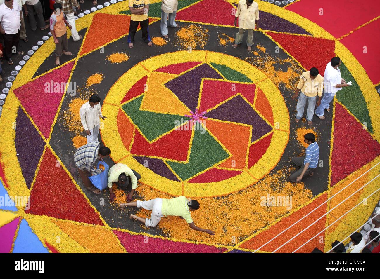 People making colorful flower Rangoli on road, Ganesh Festival, Sangli