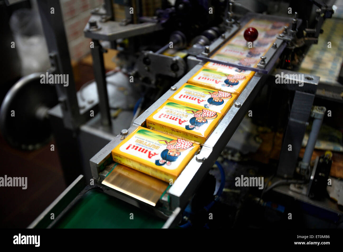 Packed Amul butter in wrappers coming out in Amul factory in Anand ; Gujarat ; India Stock Photo