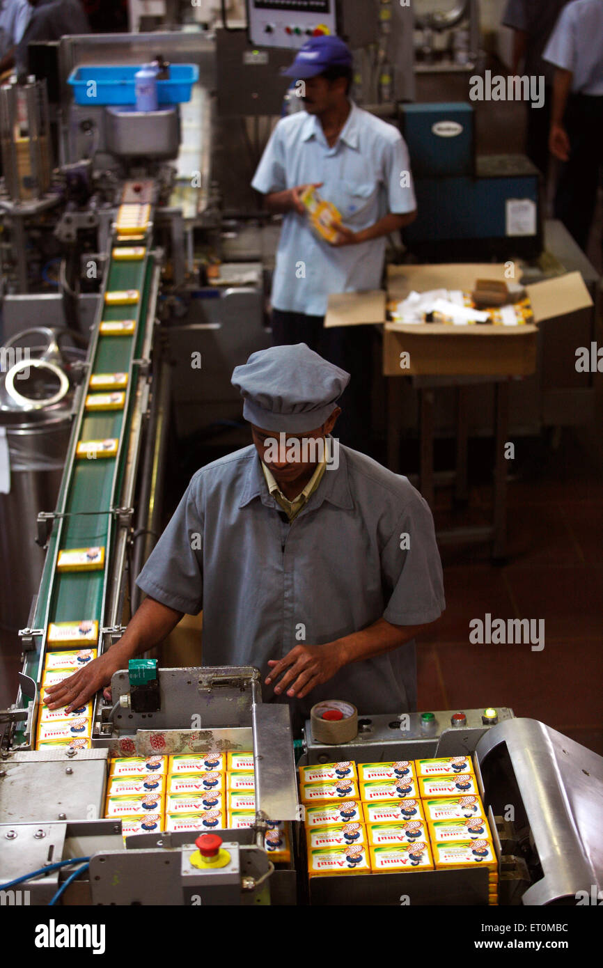 Worker collecting and packing butter in packets coming out at Amul factory in Anand ; Gujarat ; India Stock Photo