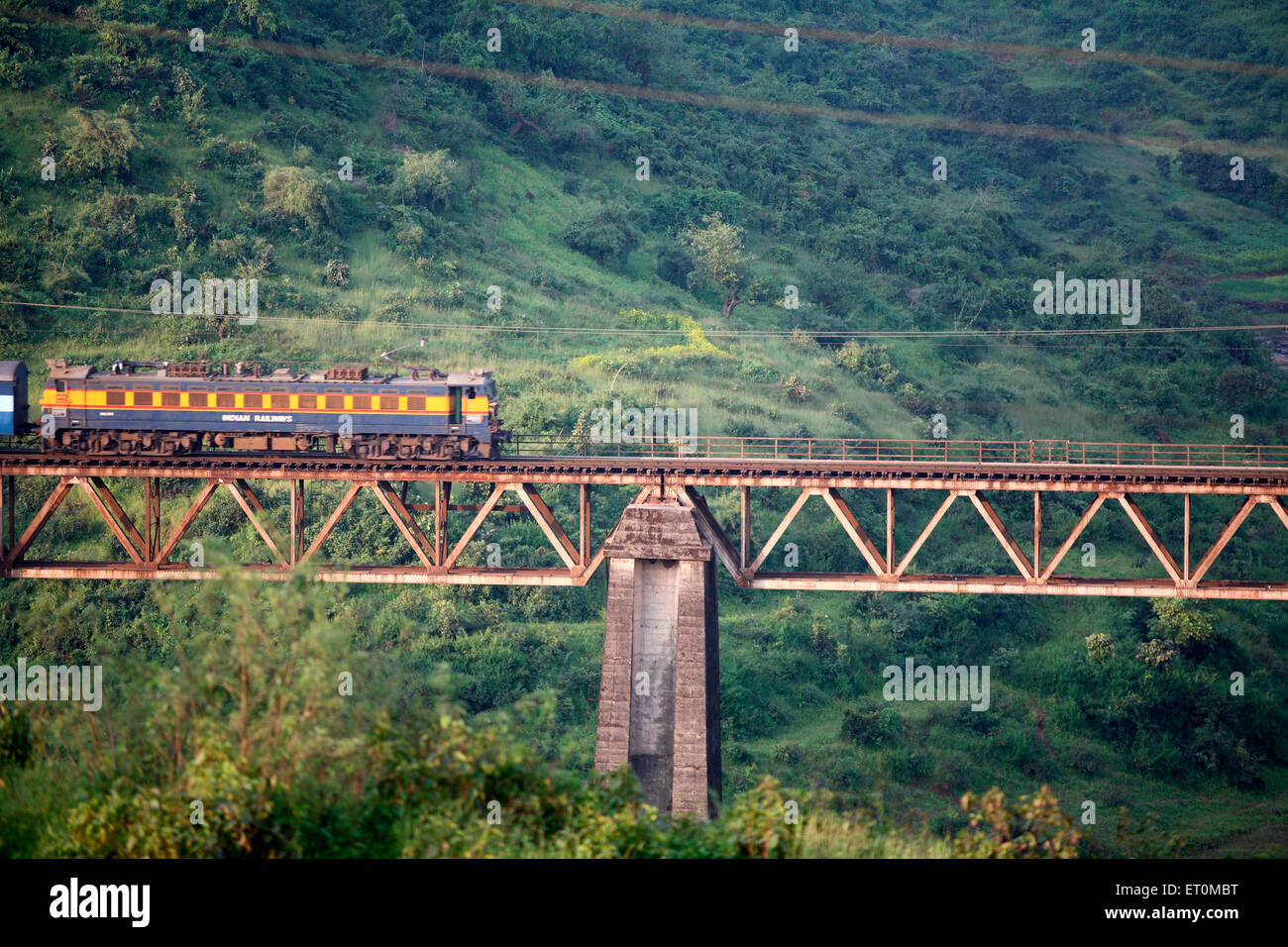 Indian Railways train passing by heightened up bridge at Igatpuri near Nasik in Maharashtra ; India Stock Photo