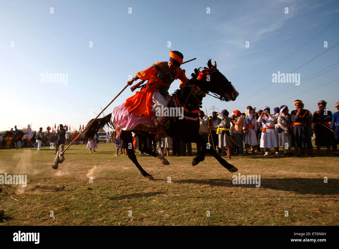 Nihang or Sikh warrior carrying spear doing tent pegging riding on horse Hola Mohalla festival Anandpur sahib punjab india Stock Photo