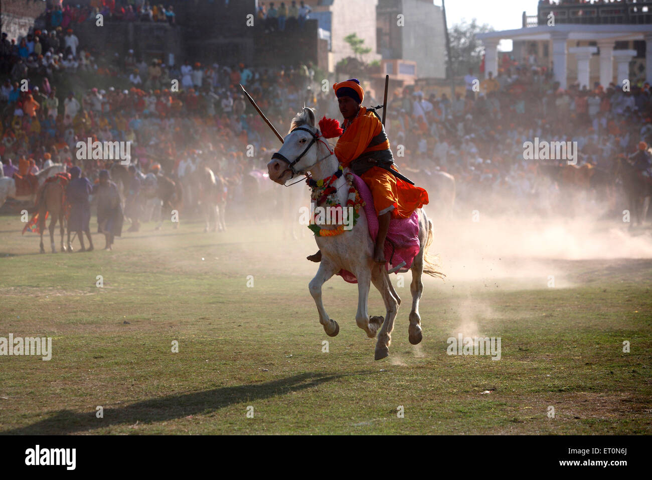 Nihang or Sikh warrior carrying spear and rifle performing stunts riding on horse during  Hola Mohalla festival at Anandpur Stock Photo