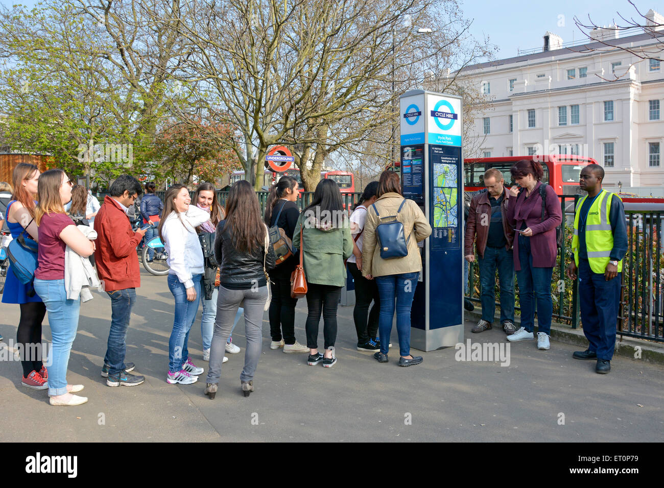 Queue of tourist people at cycle hire docking station with assistant available to help if required Hyde Park Corner London England UK Stock Photo