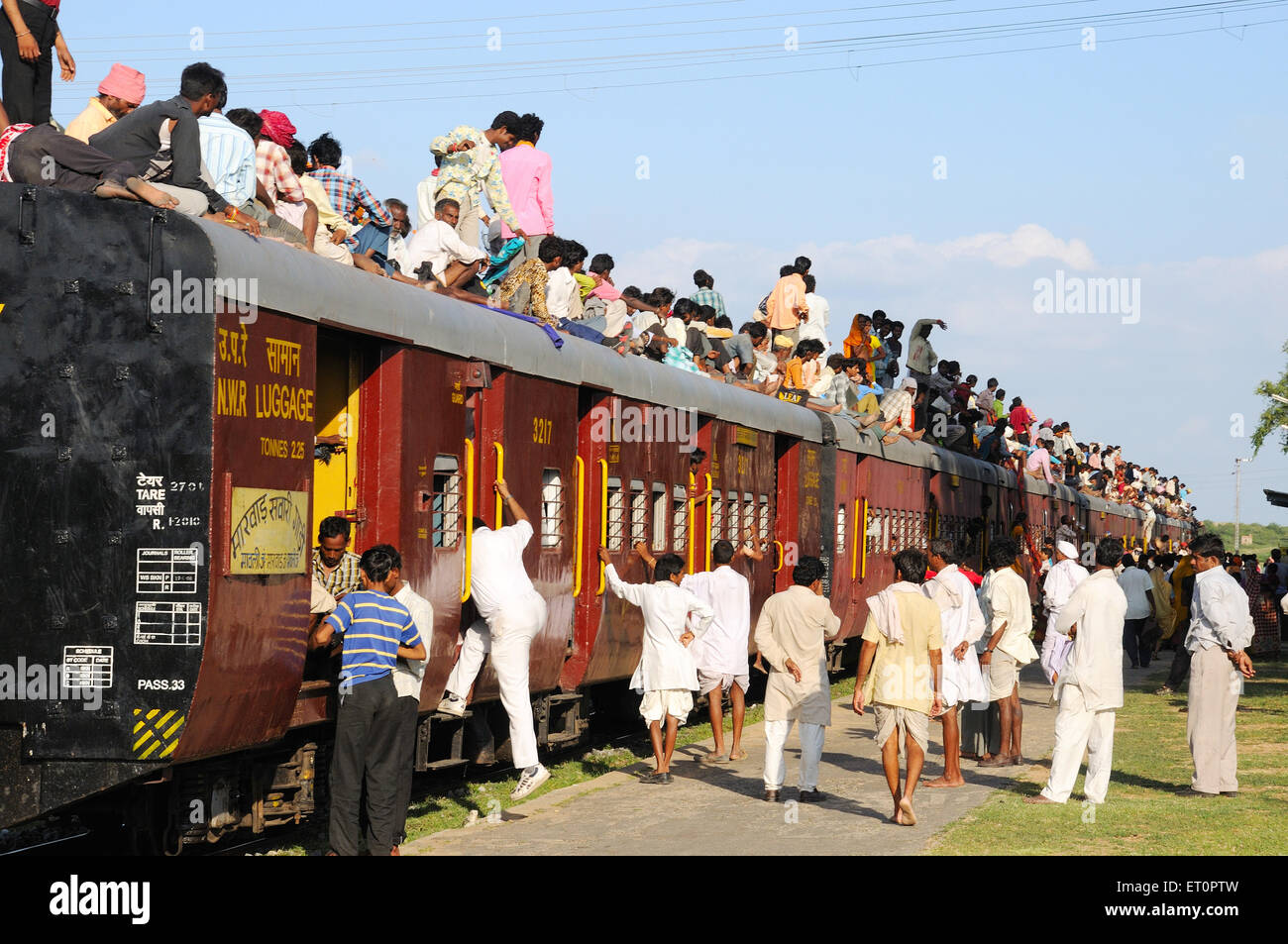 People climbing on roof of train for risky travel Marwar railway station Rajasthan India Stock Photo