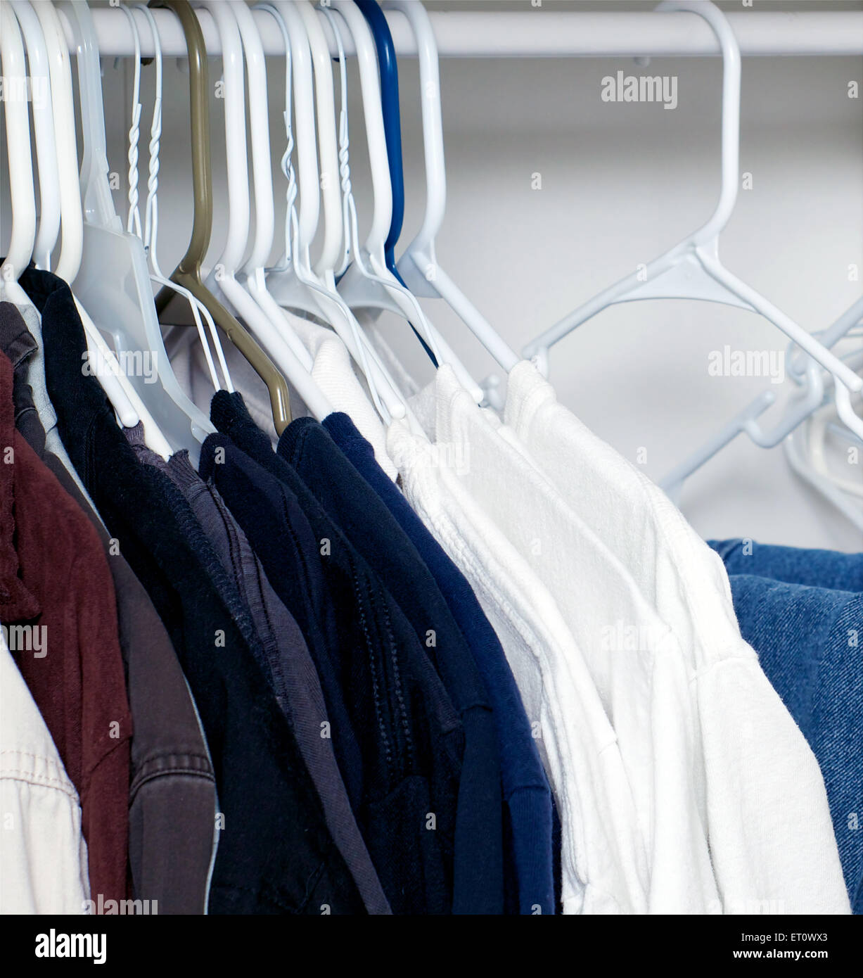 Looking inside a man's closet or armoire full of clothes hanging on