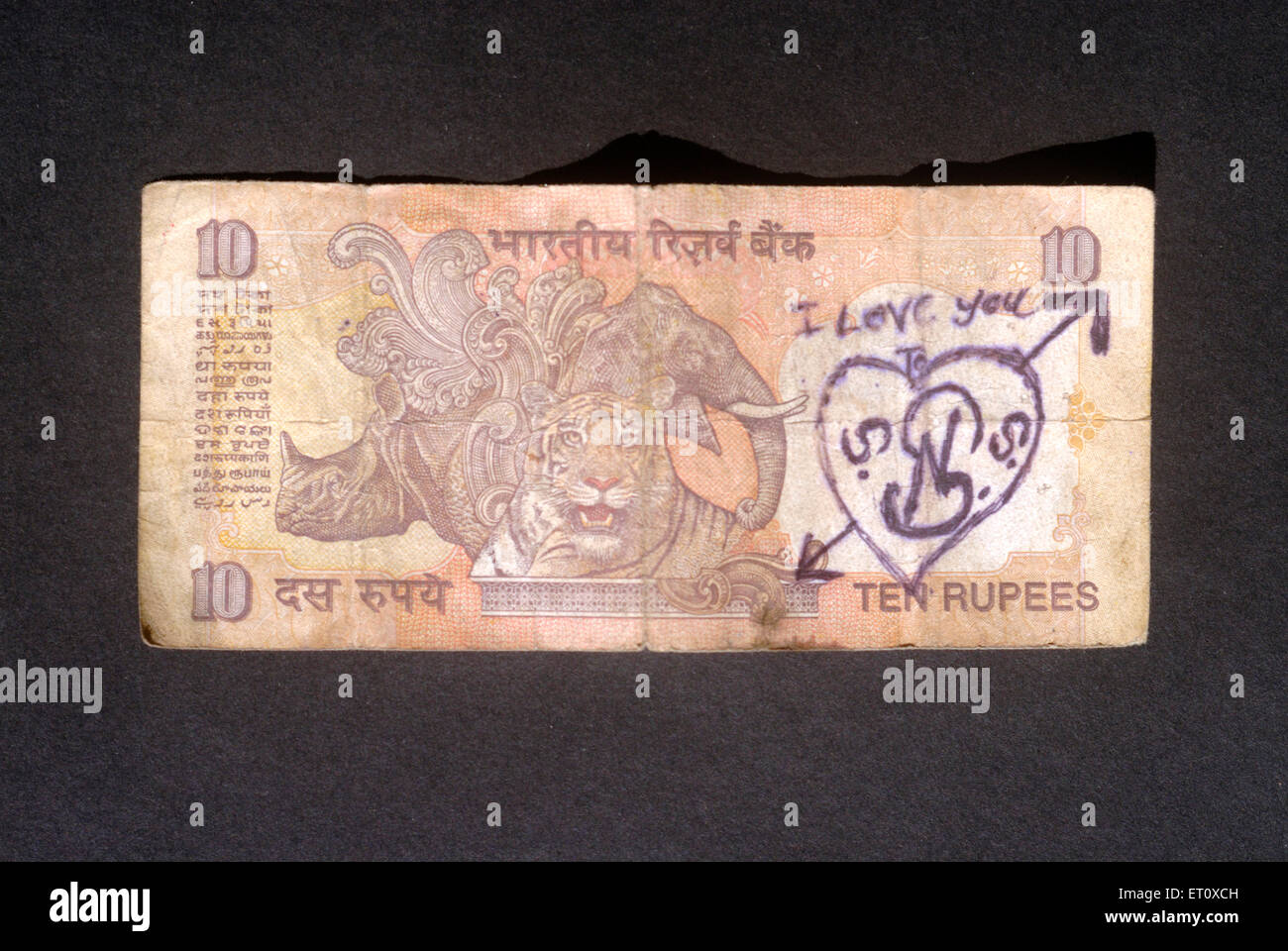 Ten rupees note damaged by writing I Love you and drawing love sign heart on black background Stock Photo