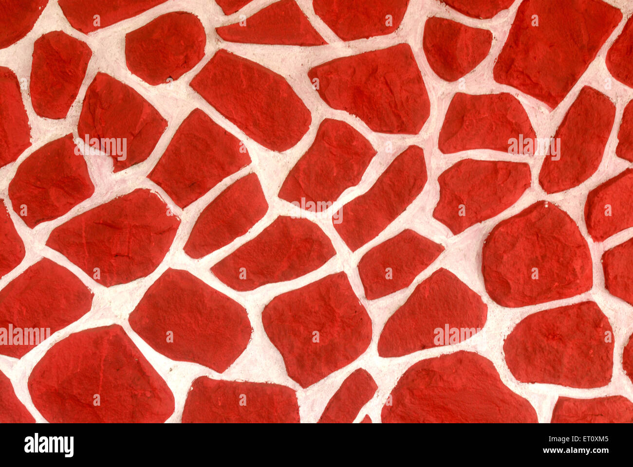 Uncaused rubble masonry wall painted in red color, India Stock Photo