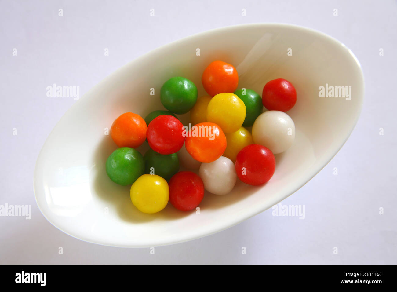 Colourful sweet and sour ball or marble in oval plate on white background Stock Photo