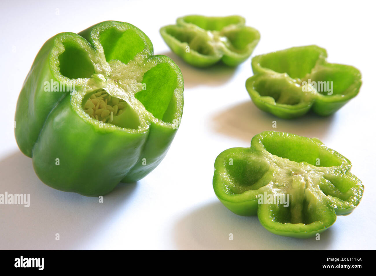 Spices ; half cut green chillies capsicum shimla mirch capsicum annuum capsicum frutescens on white background Stock Photo