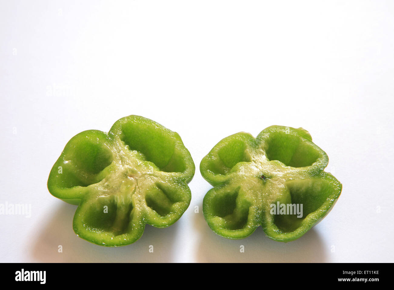 Spices ; half cut green chillies capsicum shimla mirch capsicum annuum capsicum frutescens on white background Stock Photo