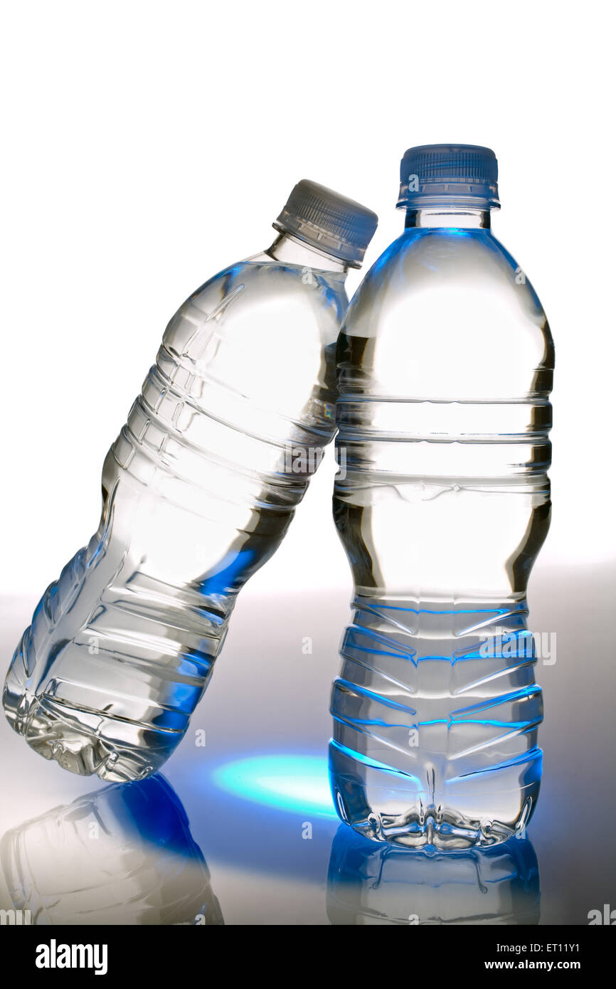 Two clear environmentally friendly plastic bottles of drinking water.  One upright and on leaning against the upright bottle. Stock Photo