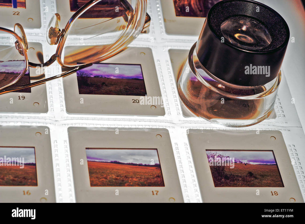 Slides (Transparencies) on a Light Box with Magnifying Loupe and Eyeglasses-Close up. Stock Photo