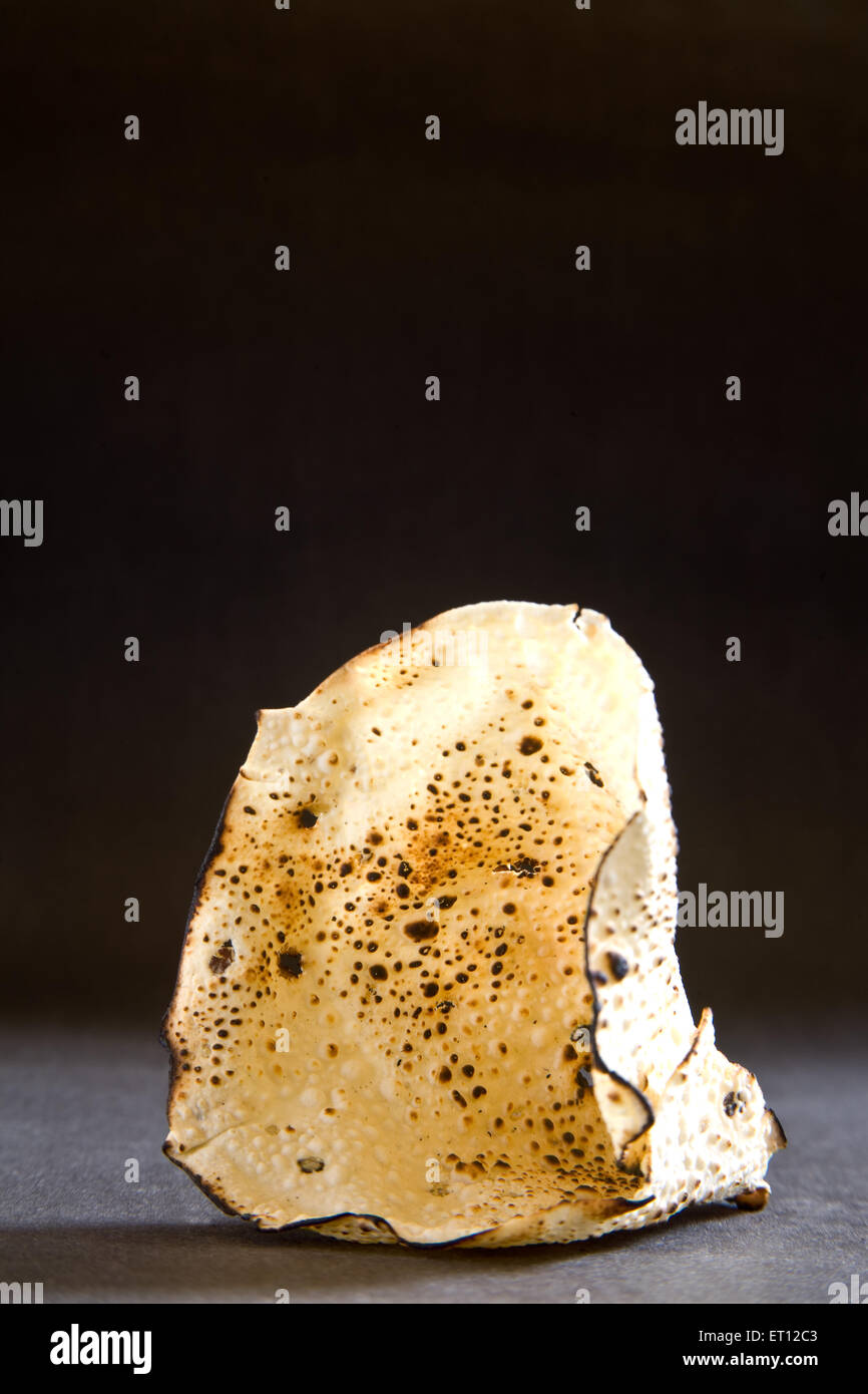 roasted papad, papadum, poppadom, Indian snack, cracker, cone shape, black background Stock Photo