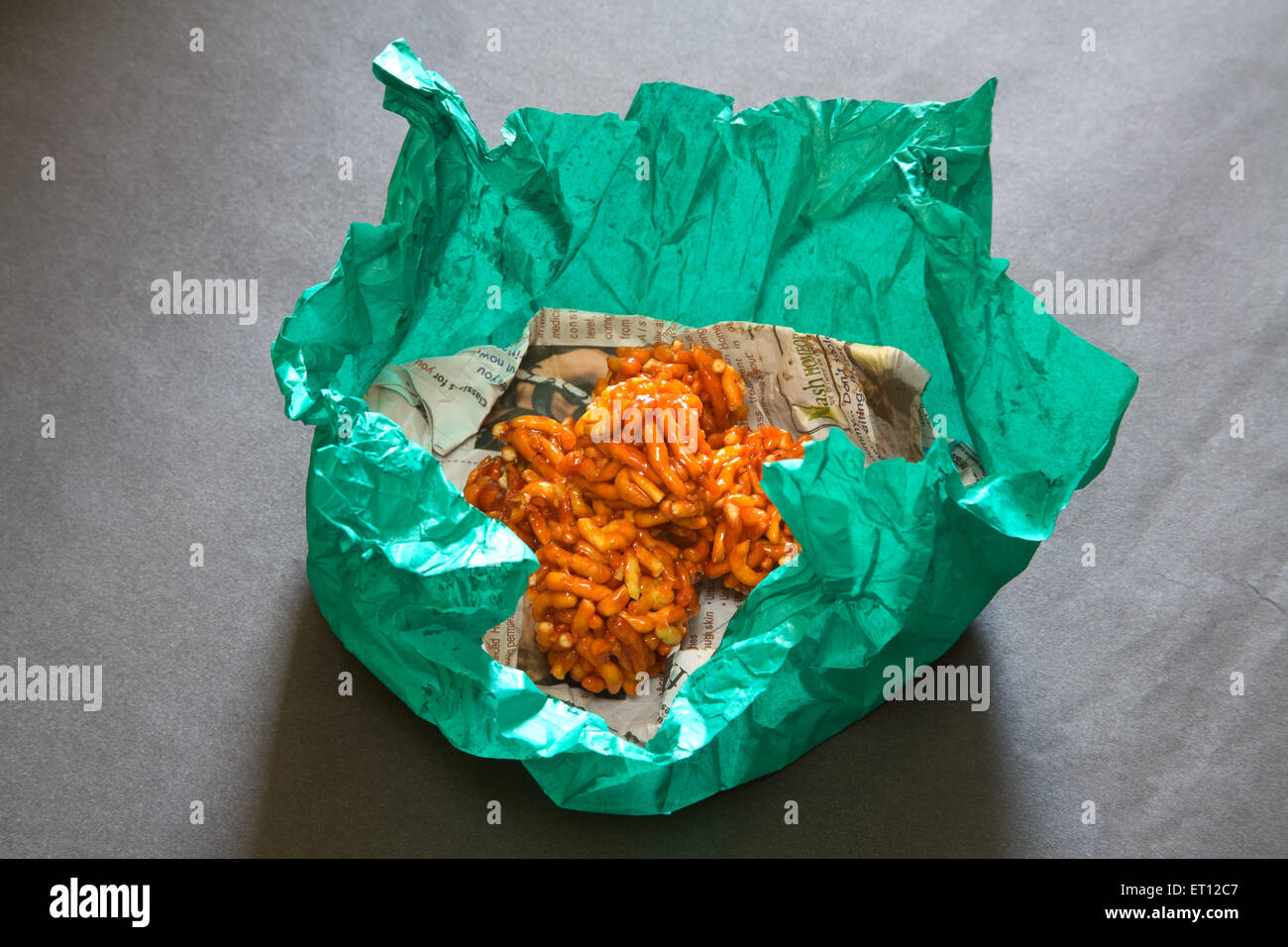 Indian mithai ladoo of gathia and jaggery on newspaper and green wrapper on black background 20 April 2010 Stock Photo