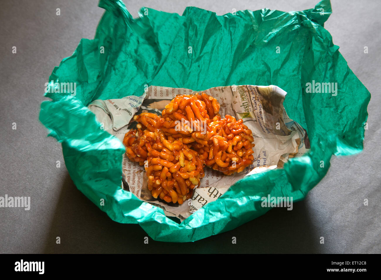 Indian mithai ladoo of gathia and jaggery on newspaper and green wrapper on black background 20 April 2010 Stock Photo