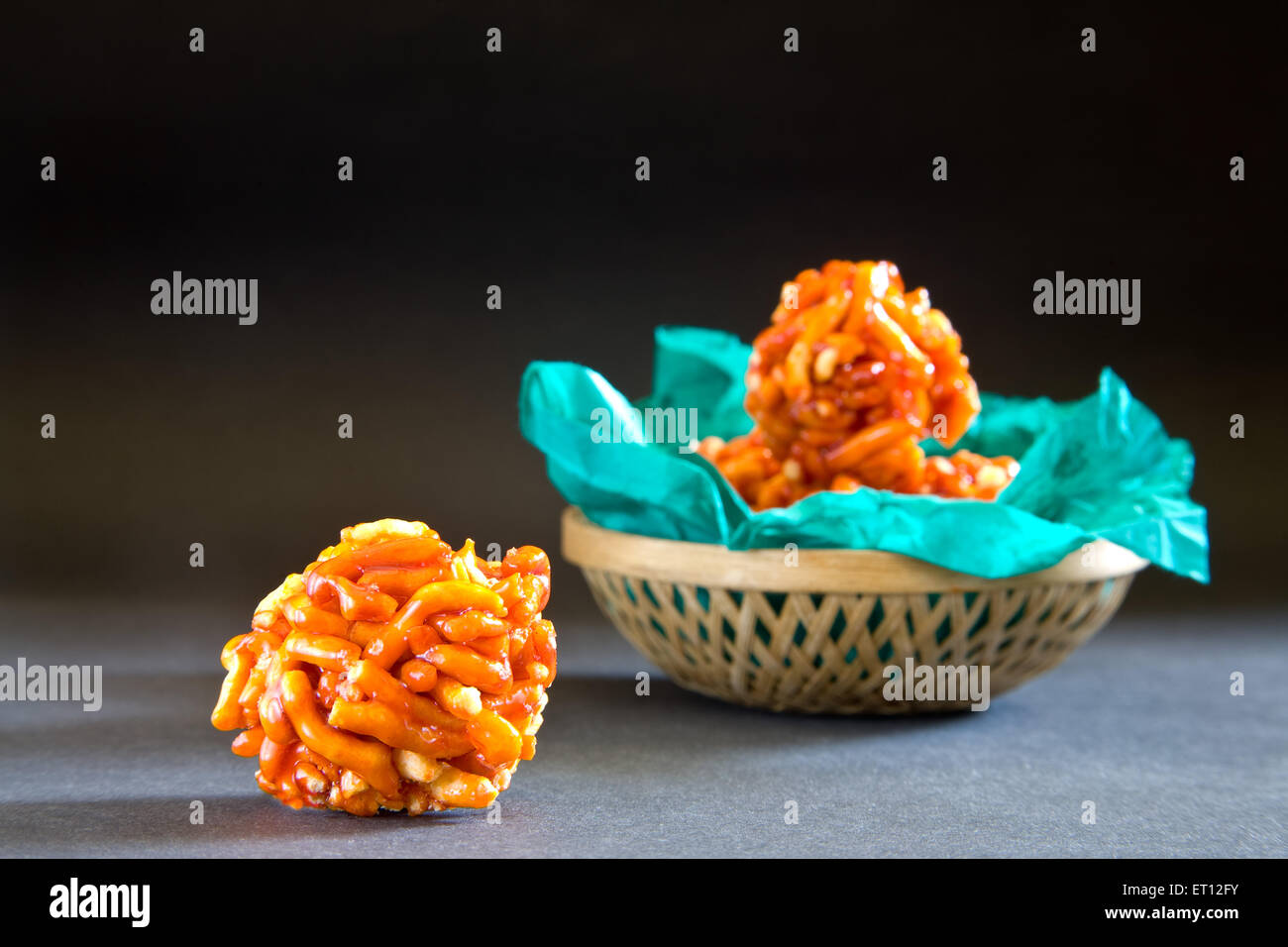 Indian mithai ladoo of gathia and jaggery in green wrapper in cane basket on black background 20 April 2010 Stock Photo