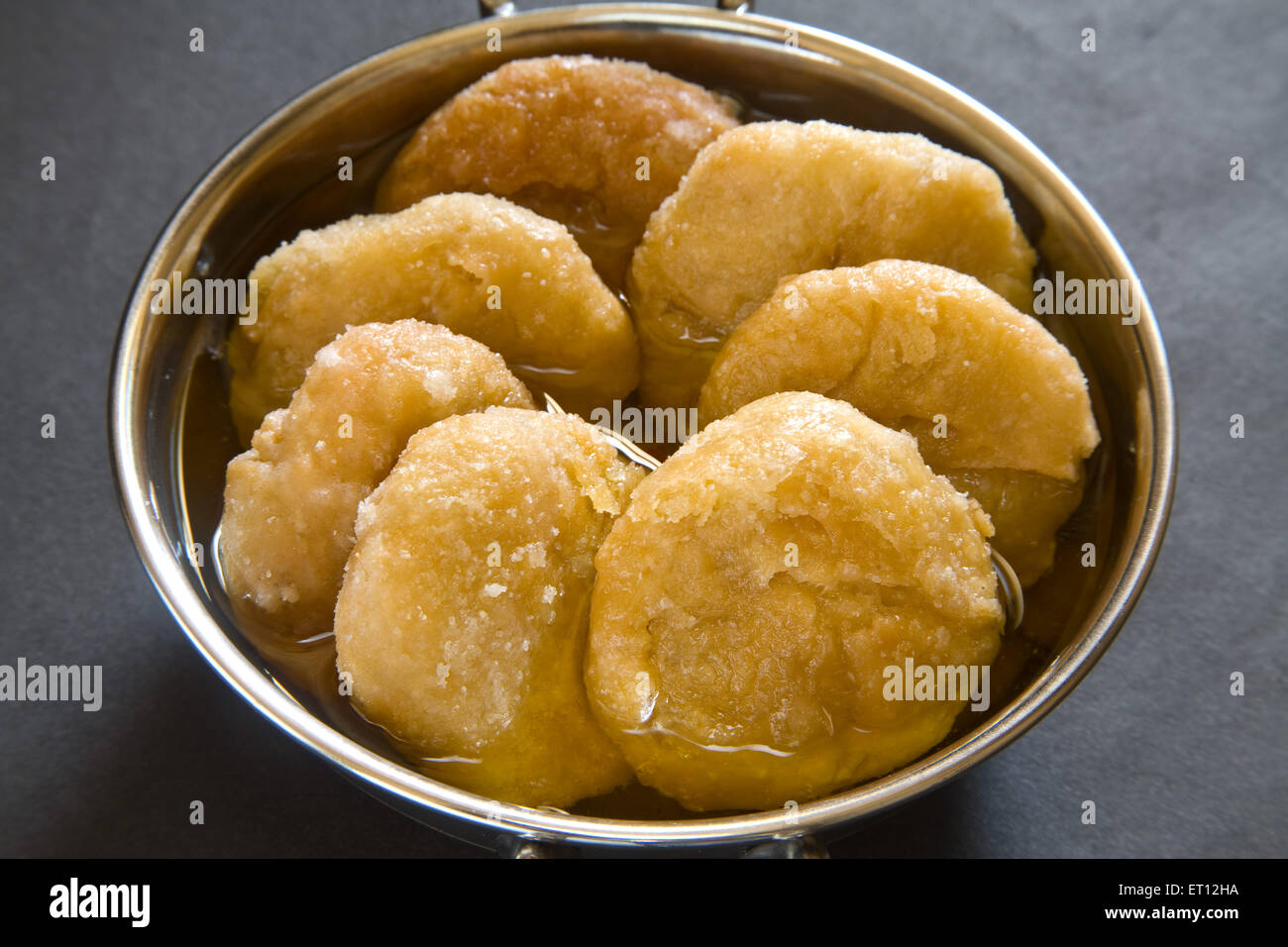 Indian sweet ghari ghaari dipping in sugar syrup in steel kadahi on black background 20 April 2010 Stock Photo