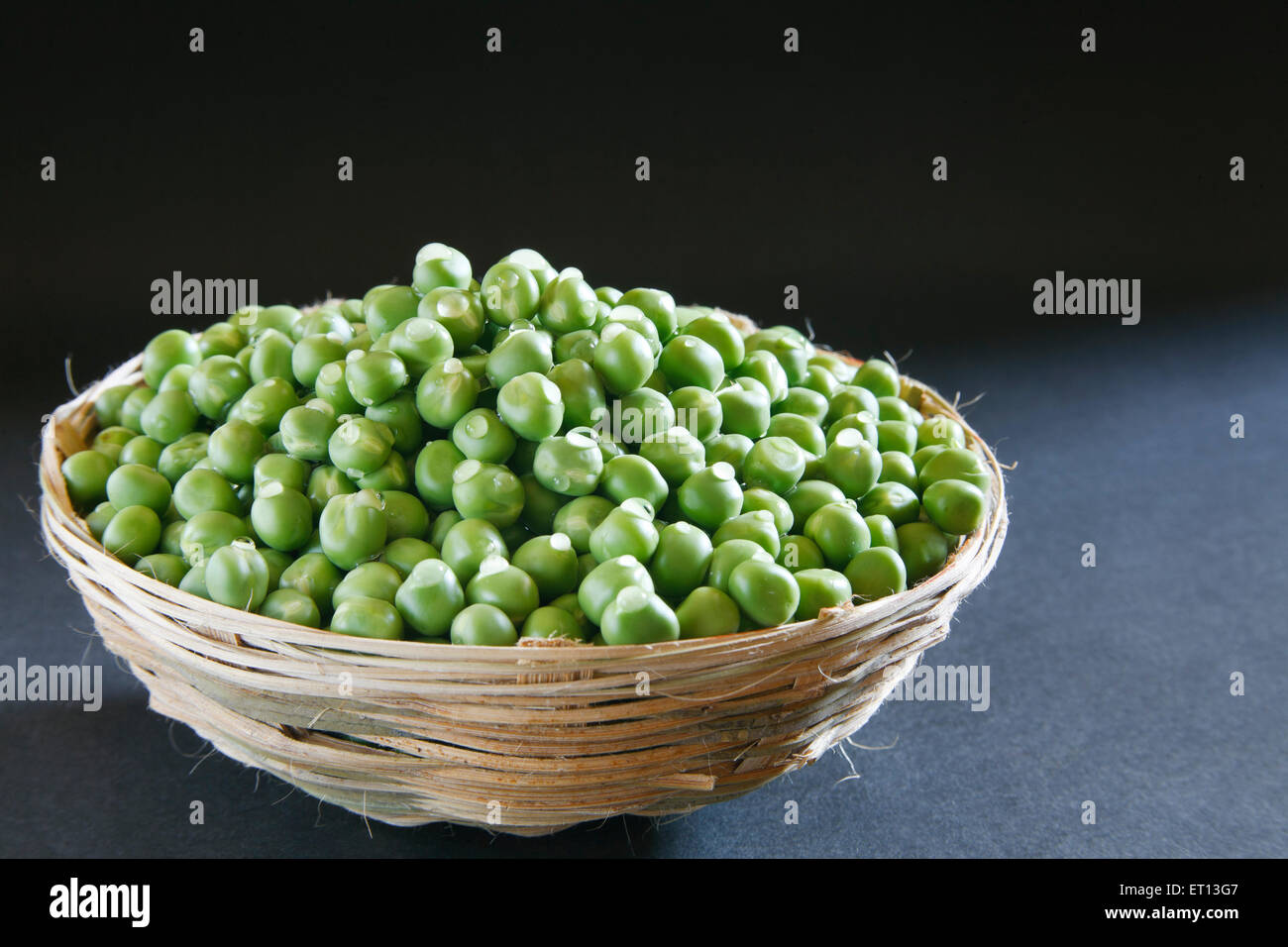 Green peas in cane basket on black background Stock Photo