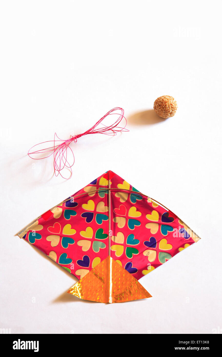 Colourful kite threads and sweet tilgur or til gul sesame laddoos for Makara Sankranti festival on white background Stock Photo