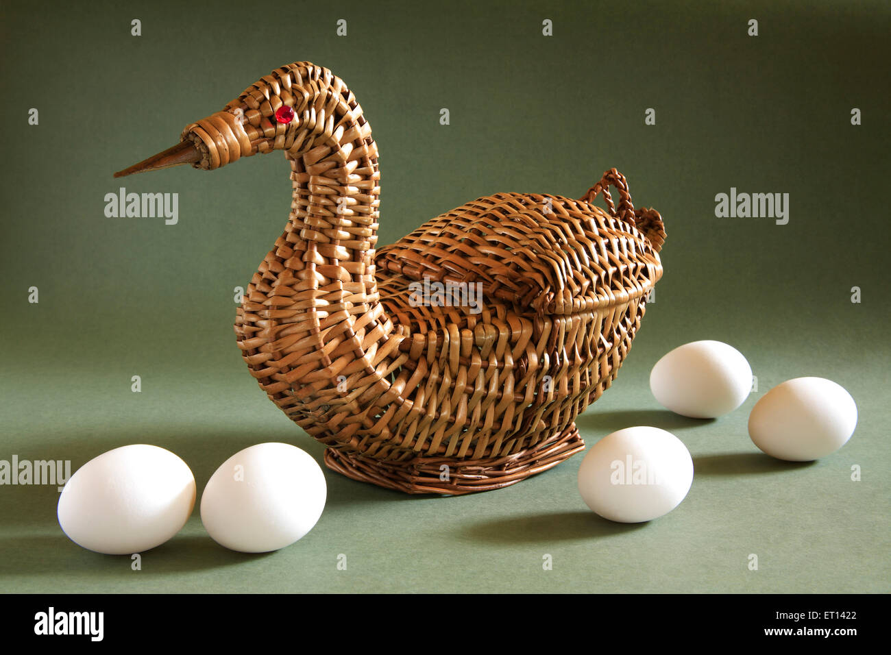 Artistic cane basket shape of duck with eggs on green background Stock Photo