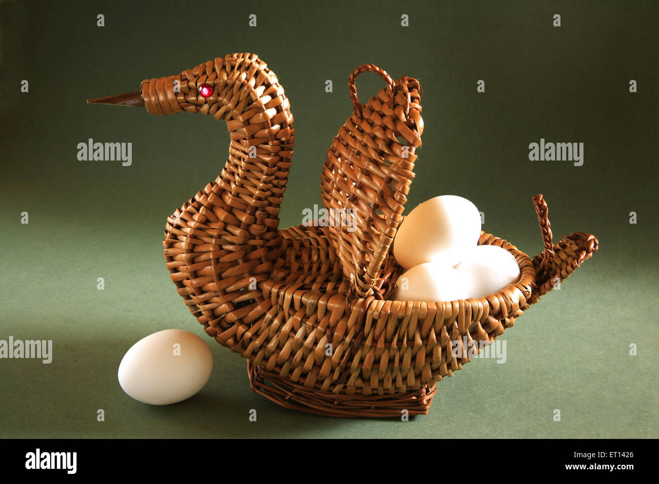 Artistic cane basket shape of duck with eggs on green background Stock Photo