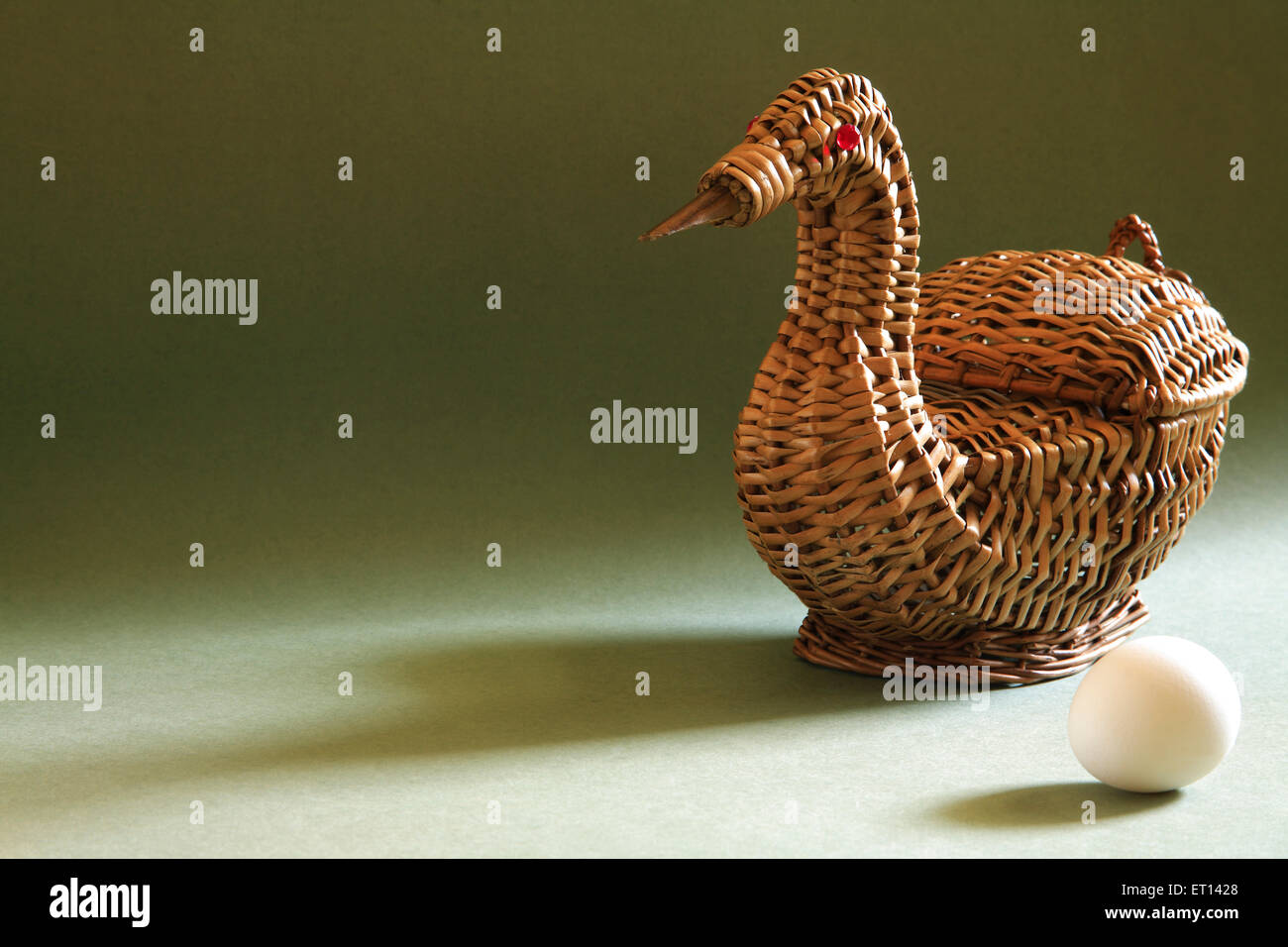 Artistic cane basket shape of duck with single egg on green background Stock Photo