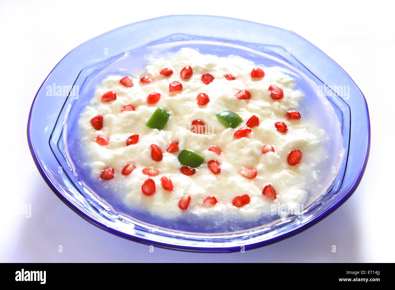 Fruit salad , pomegranate and curd with green capsicum in blue round bowl on white background Stock Photo