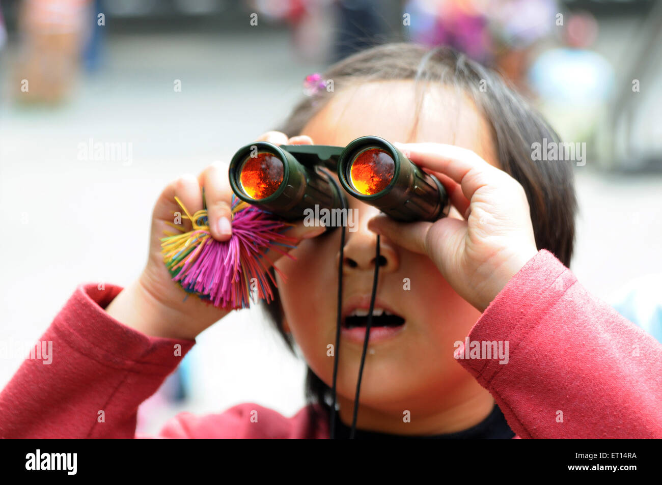 Chinese girl looking through mini binocular, Beijing, China Stock Photo