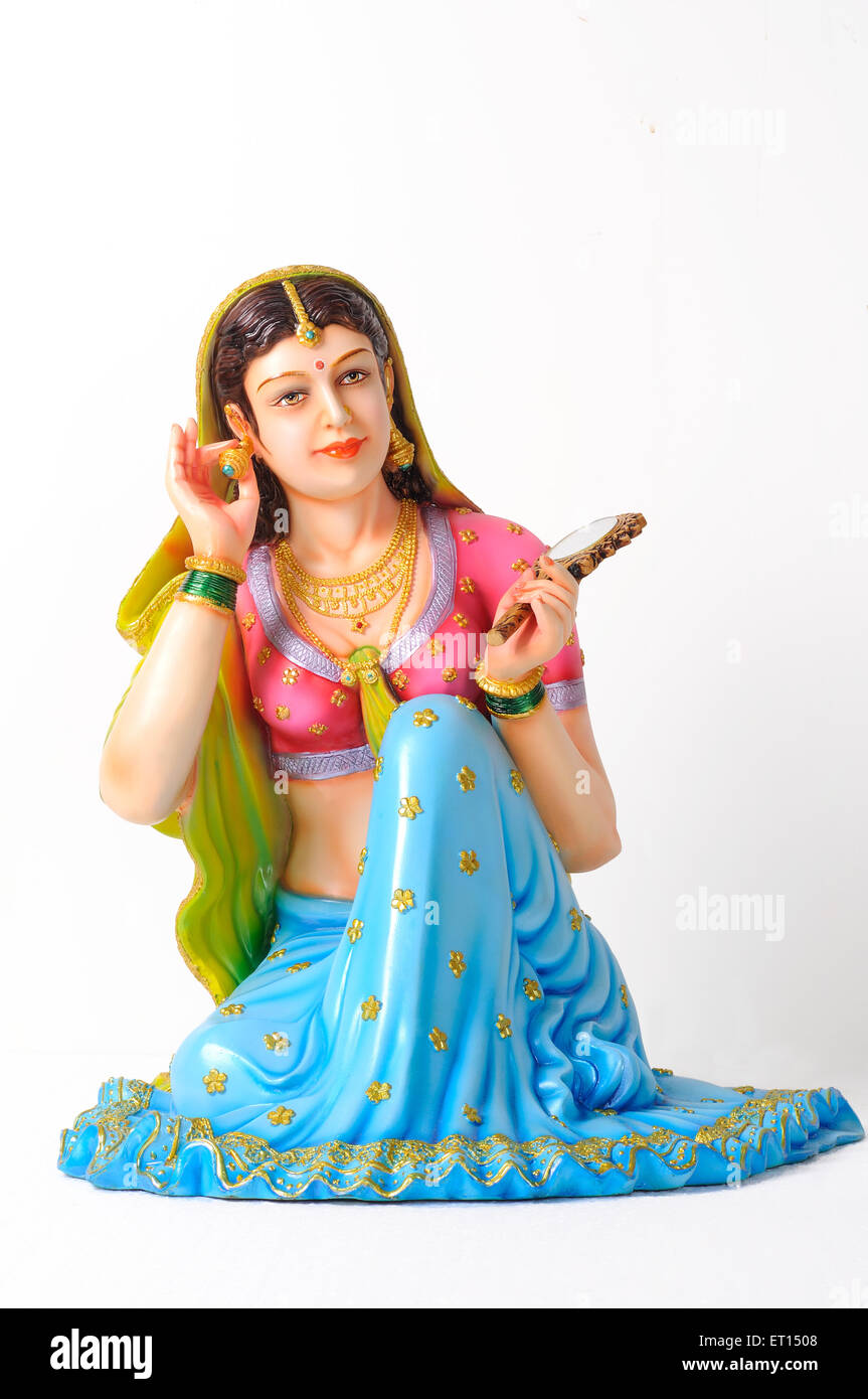 Clay figurine ; statue of rajasthani young girl wearing earring with mirror in her left hand Stock Photo