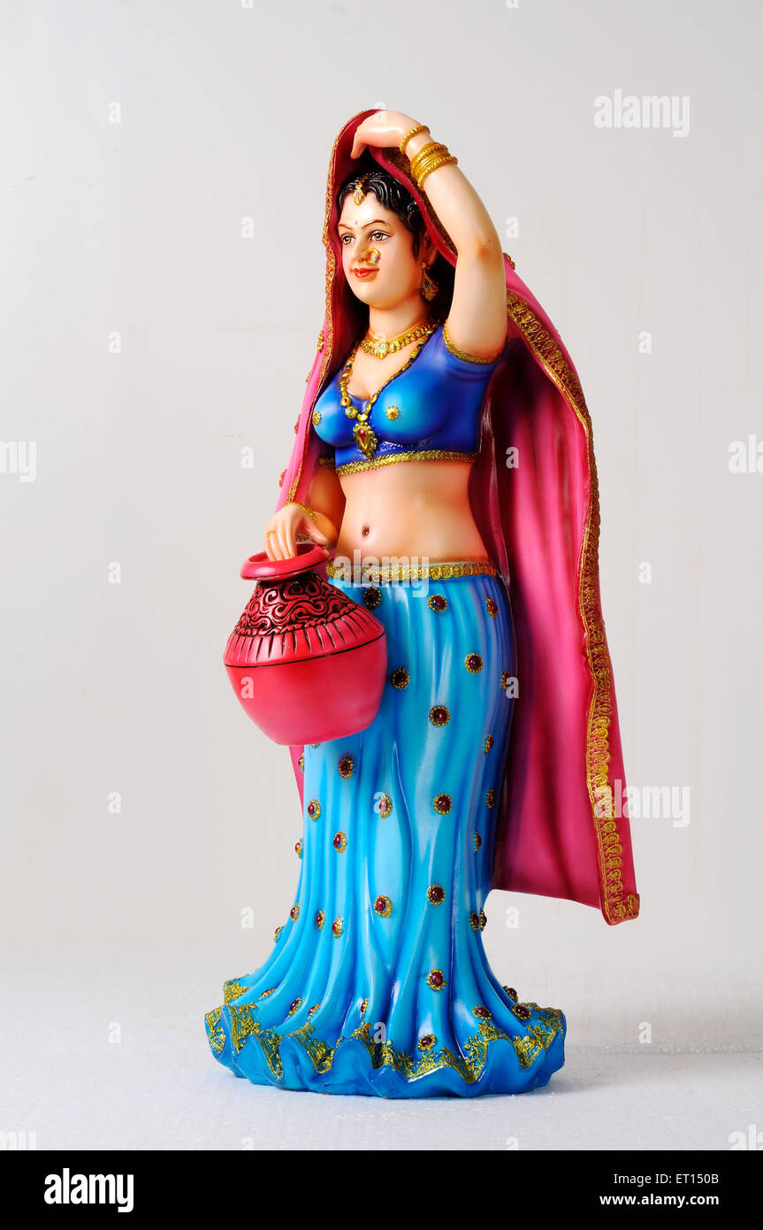 Clay figurine ; statue of rajasthani young girl with sari pallu on her head and holding colourful pot Stock Photo