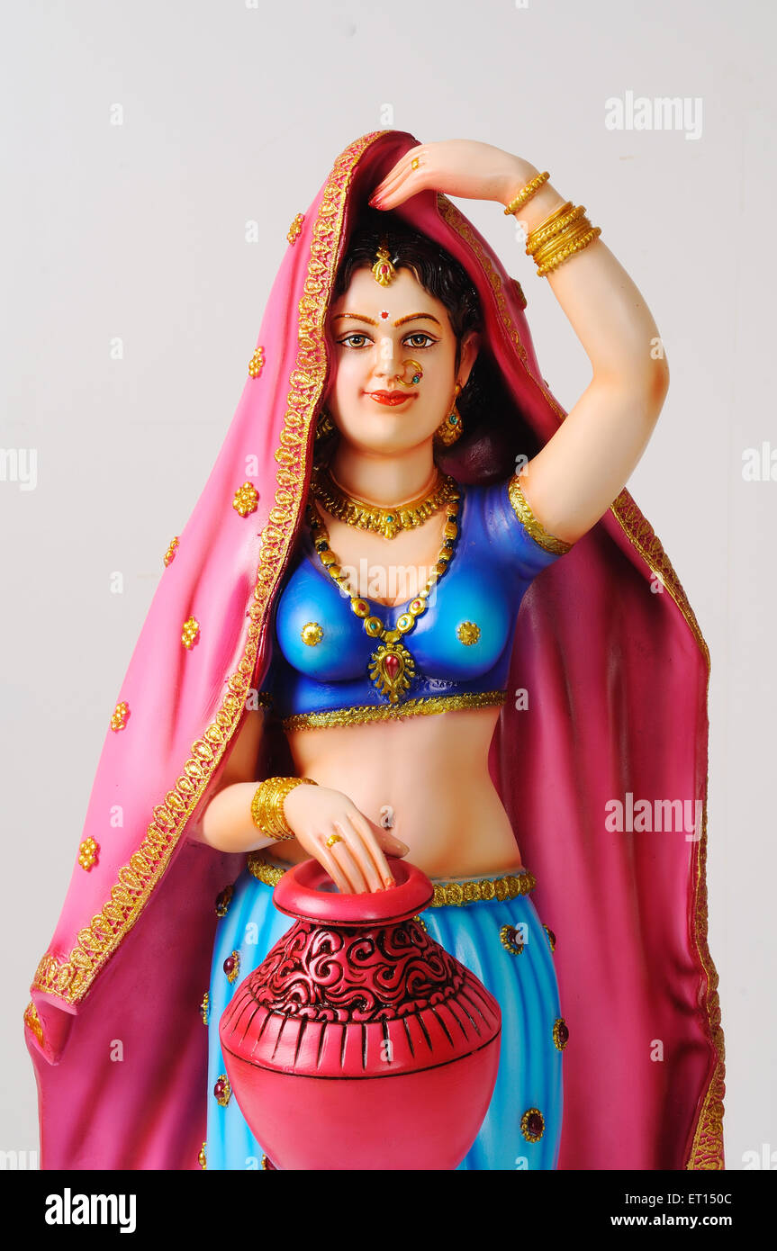 Clay figurine ; statue of rajasthani young girl with sari pallu on her head and holding colourful pot Stock Photo