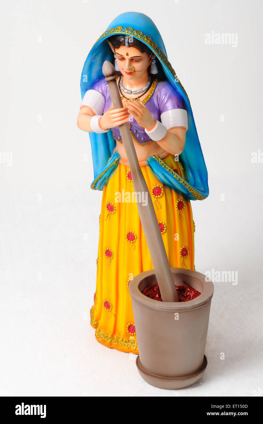 Clay figurine ; statue of rajasthani woman pounding spices red chillies in mortar with pestle Stock Photo