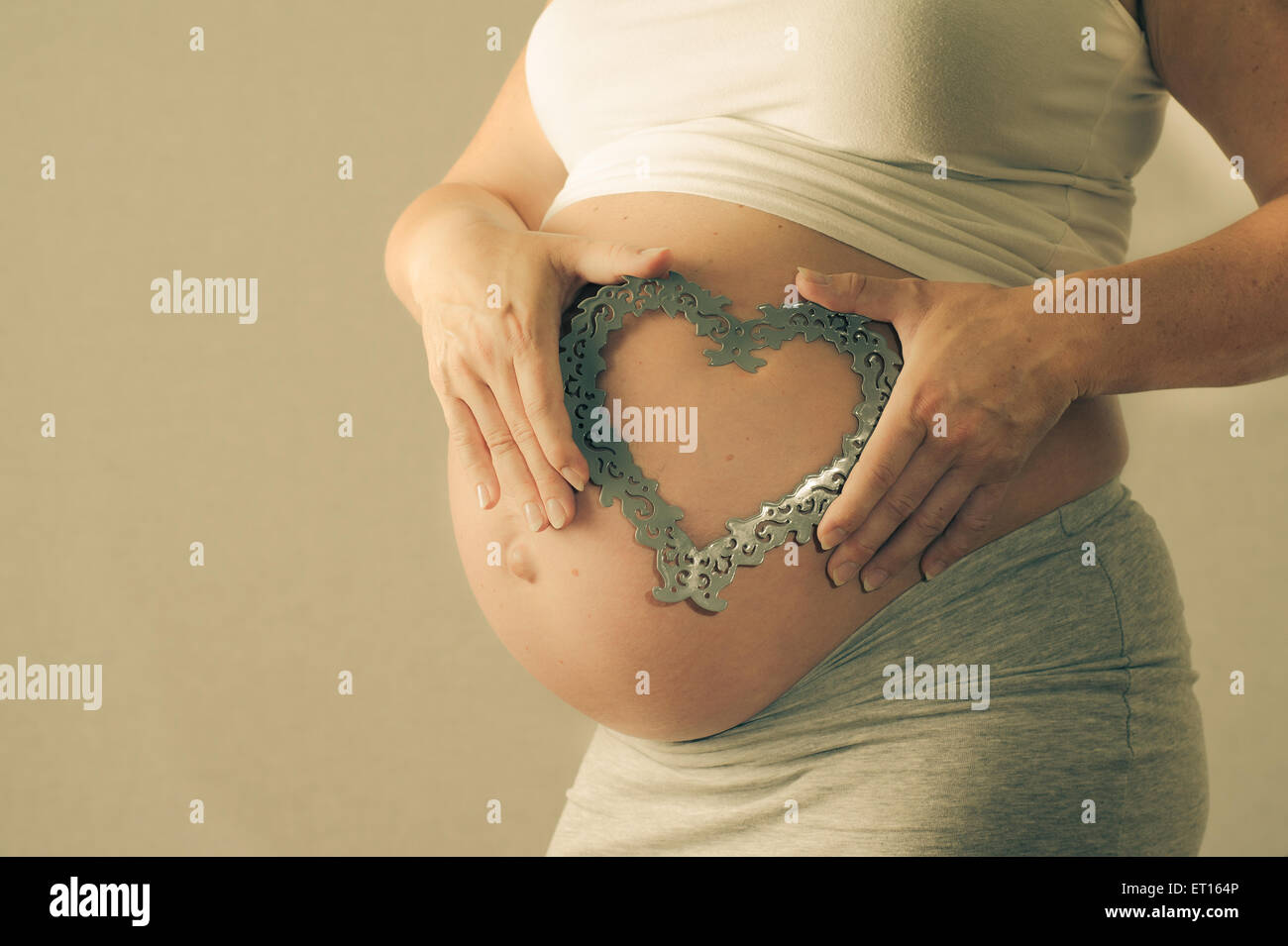 Pregnant woman maternity picture of her belly with a heart Stock Photo